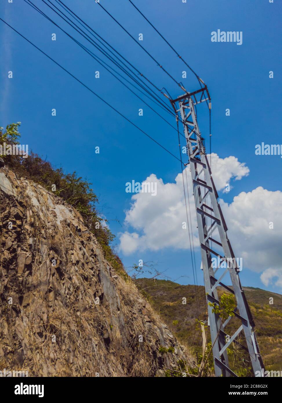 Asphalte sec route d'automobile vide avec pôle électrique près des rochers lors d'une journée ensoleillée d'été. Présentation du concept de voyage en voiture. Format vertical des articles Banque D'Images
