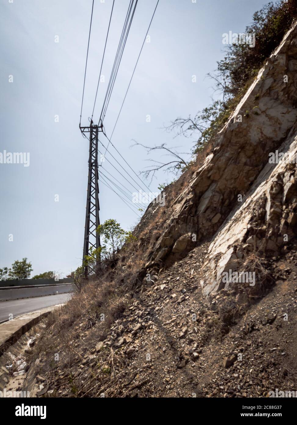 Asphalte sec route d'automobile vide avec pôle électrique près des rochers lors d'une journée ensoleillée d'été. Présentation du concept de voyage en voiture. Format vertical des articles Banque D'Images