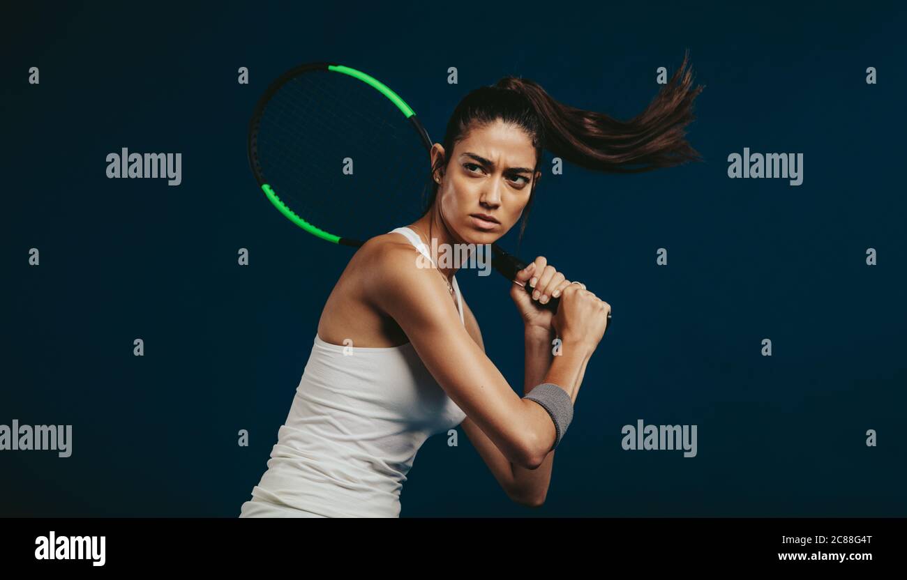 Sportswoman tenant une raquette de tennis. Joueur de tennis professionnel sur fond sombre. Banque D'Images