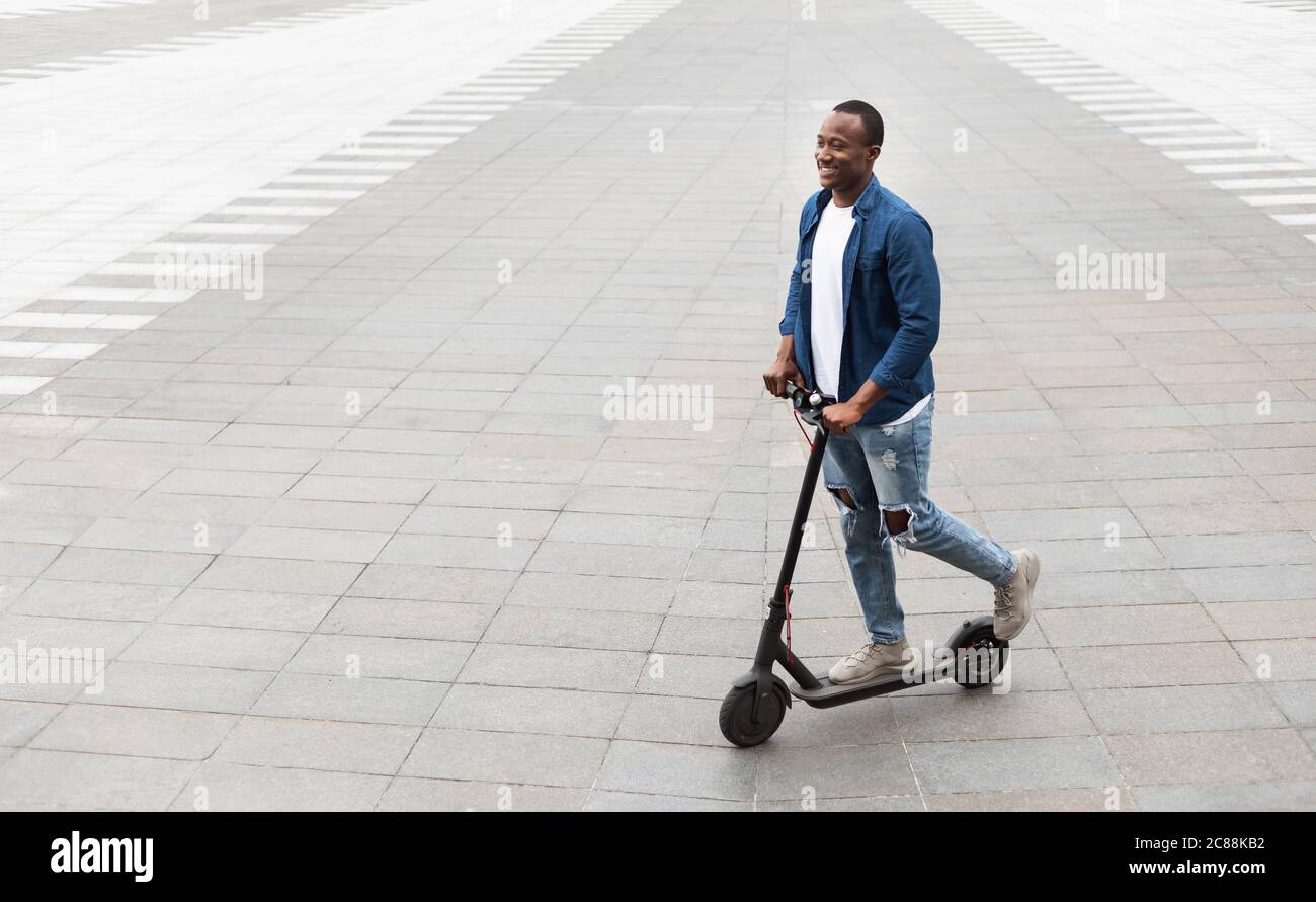 Fille souriante ayant une agréable promenade sur le scooter électrique de coup Banque D'Images