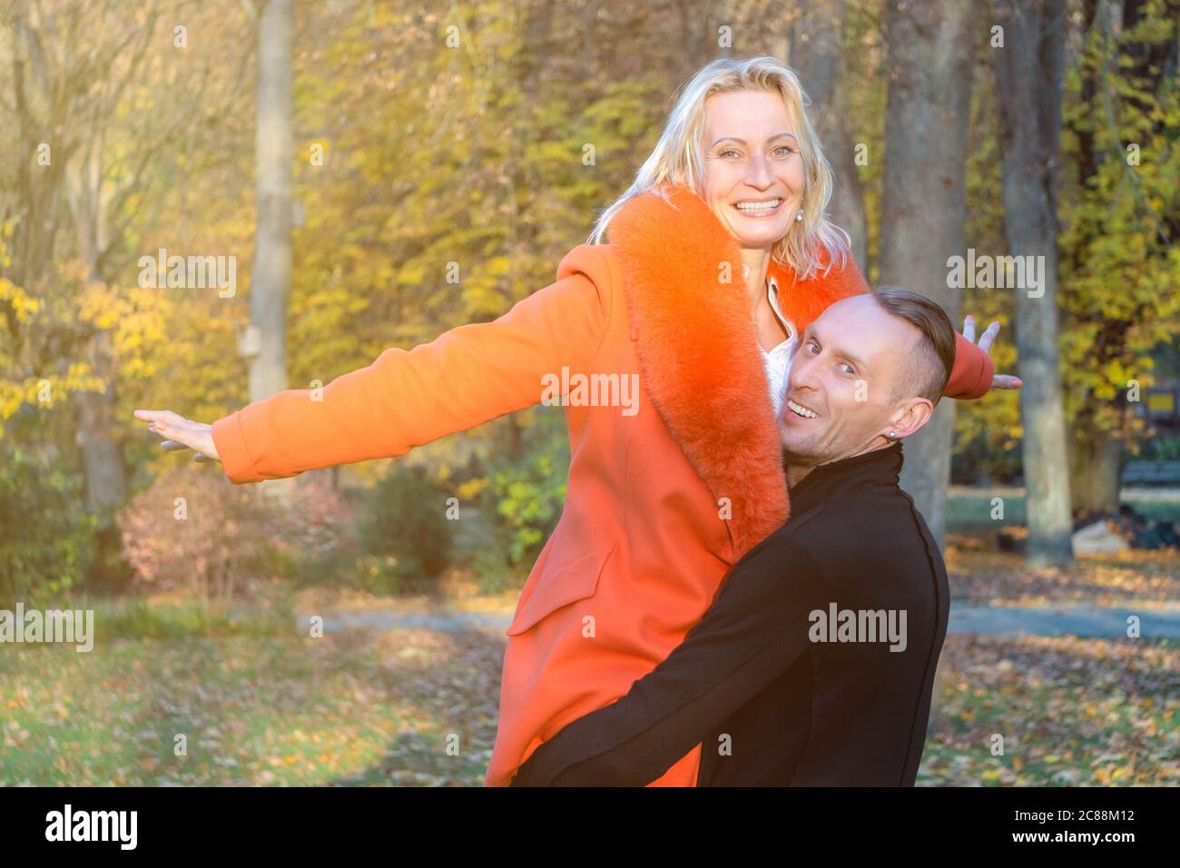 Couple d'âge moyen dans le parc d'automne. Homme souriant tenant la femme entre les mains sur fond d'automne coloré. Couple heureux sur l'arrière-plan des arbres d'automne.paire Banque D'Images