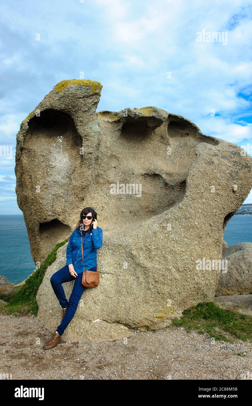 Une seule touriste féminine penchée sur l'une des spectaculaires formations rocheuses de Granite Island à Victor Harbor en Australie méridionale. Banque D'Images