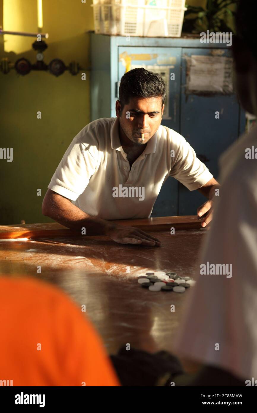 Un joueur de carrom indien adulte en position de commencer le jeu Banque D'Images