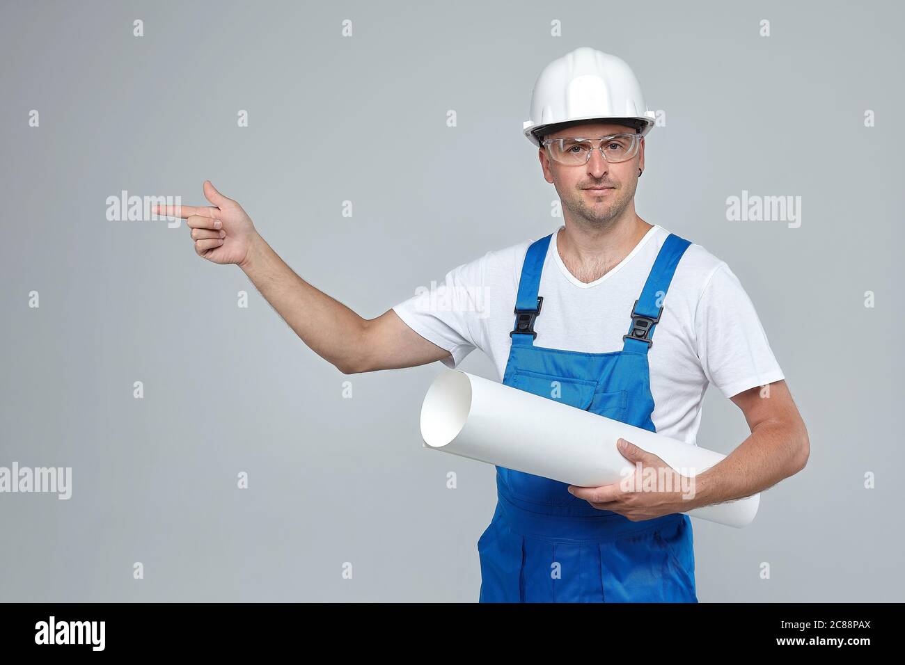 Homme adulte dans un casque de construction blanc. Le doigt pointe vers un espace vide. Concept publicitaire pour la construction Banque D'Images
