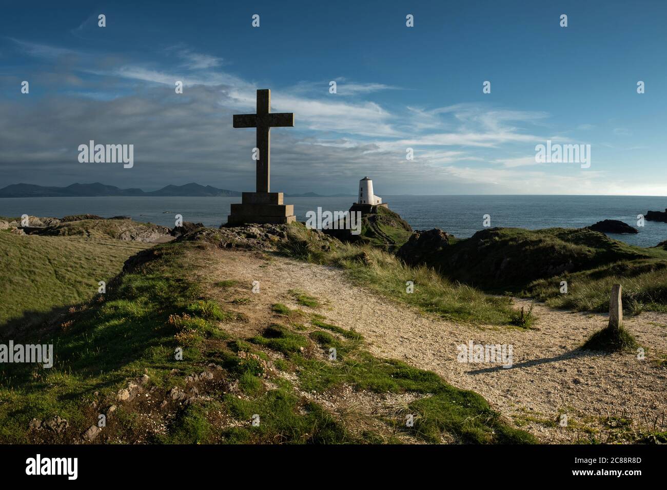Côte nord du pays de Galles avec une croix et le phare de Llanddwyn, Royaume-Uni Banque D'Images
