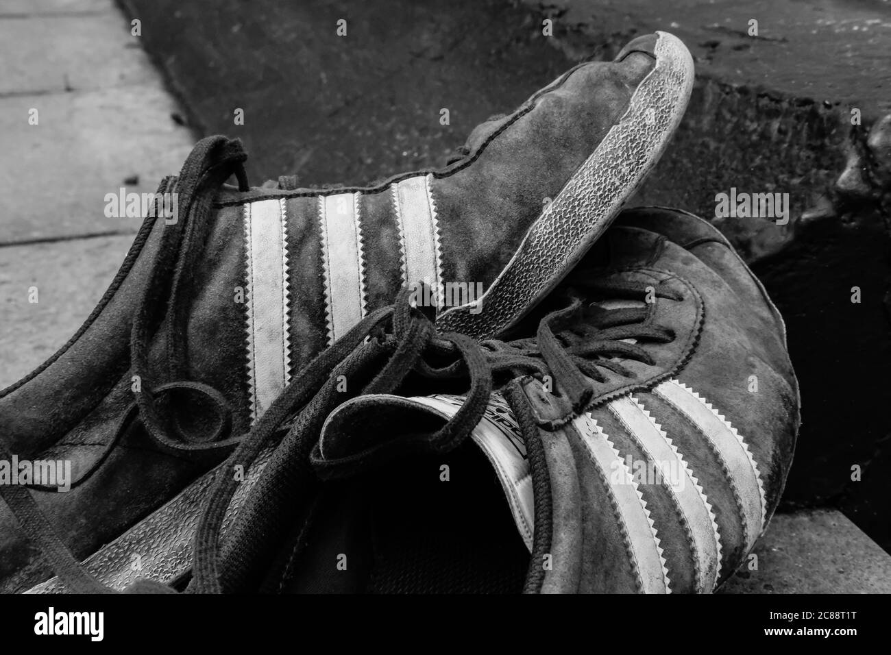 Paire de vieilles chaussures de course à pied pour hommes vues à l'extérieur par temps changeant, montrant diverses quantités de décoloration et d'usure. Banque D'Images