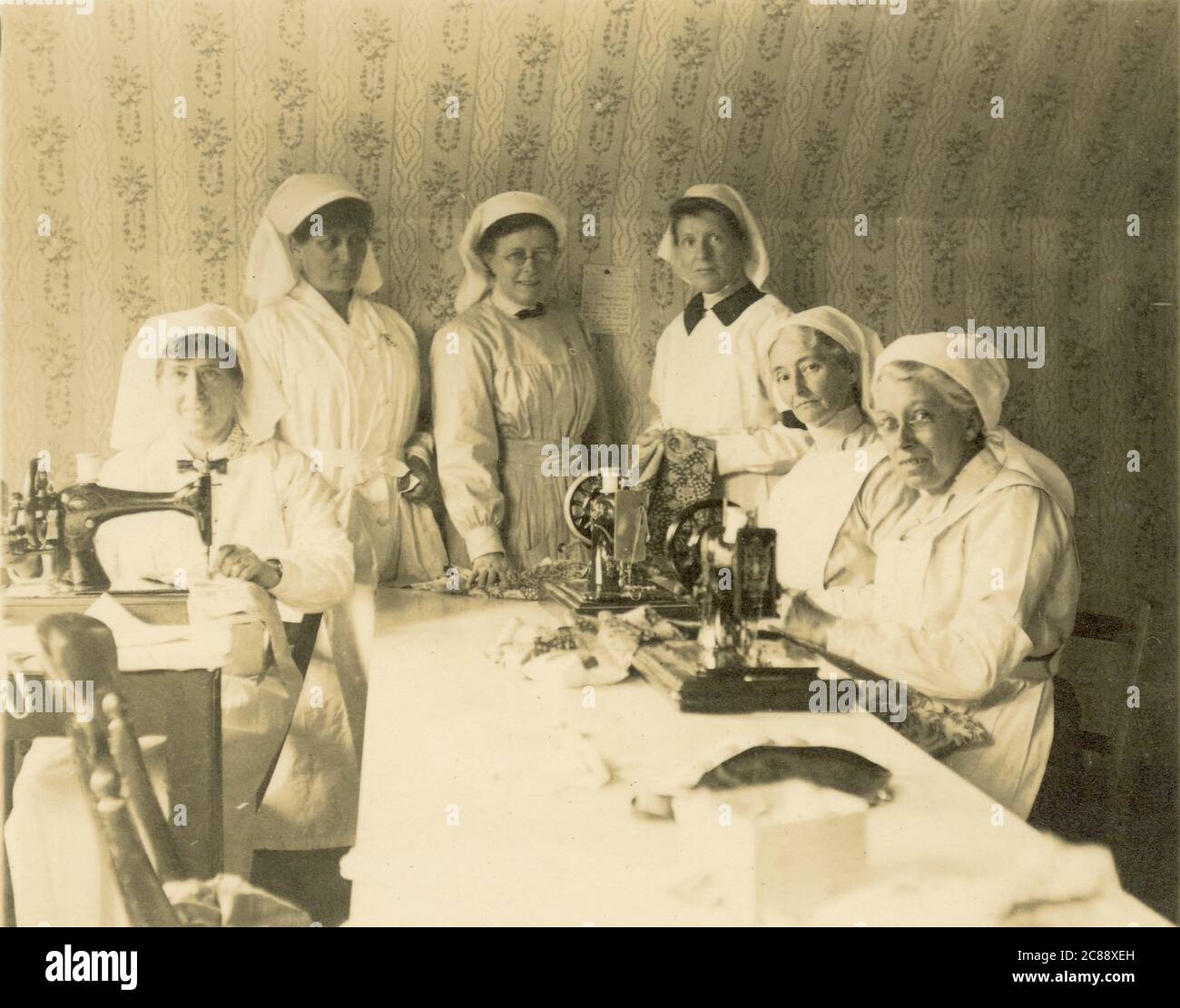 Original rare WW1 ère carte postale groupe d'infirmières fabriquant / cousant des bandages ou des pansements, abeille de couture, Royaume-Uni circa 1914-1918 Banque D'Images