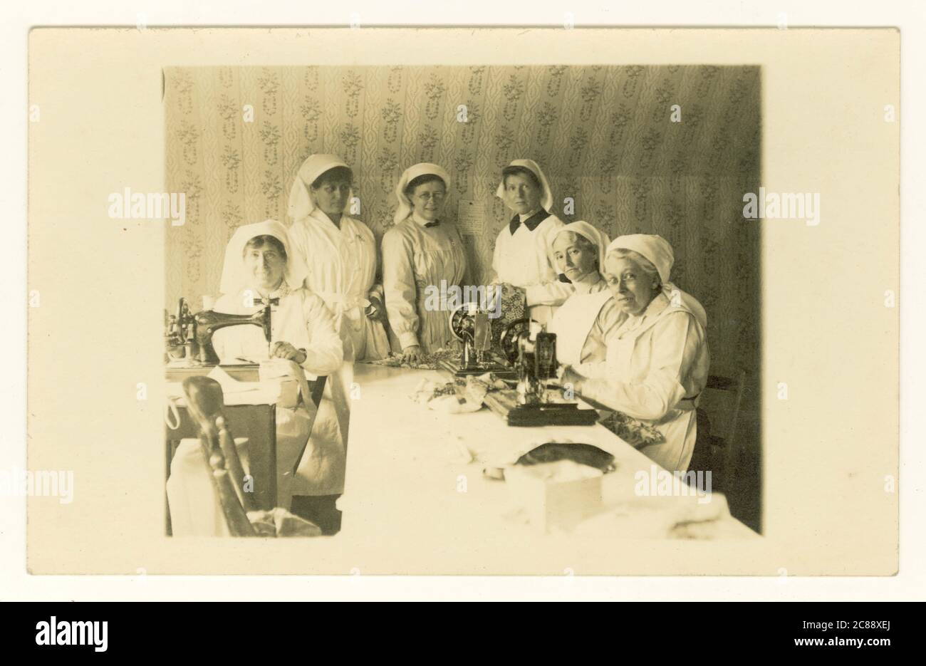 Original rare WW1 ère carte postale d'un groupe d'infirmières dévouées faisant / coudre des bandages ou des pansements, coudre des abeilles, servant leur pays pendant la Grande Guerre, Royaume-Uni vers 1914-1918 Banque D'Images