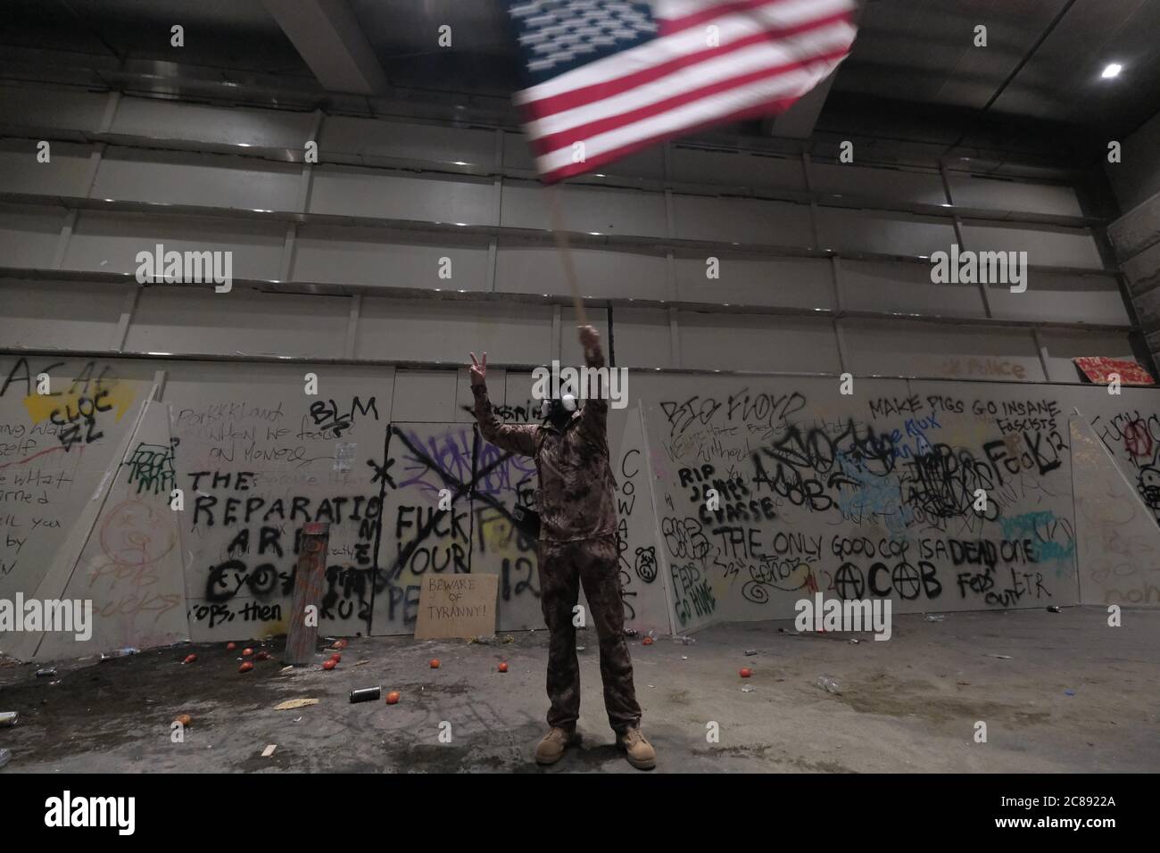 Portland, États-Unis. 21 juillet 2020. Un homme fait un drapeau américain dans les airs devant le palais de justice fédéral de Portland, en Oregon, le 21 juillet 2020. (Photo par Alex Milan Tracy/Sipa USA) crédit: SIPA USA/Alay Live News Banque D'Images