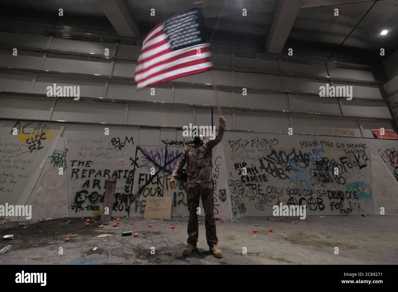 Portland, États-Unis. 21 juillet 2020. Un homme fait un drapeau américain dans les airs devant le palais de justice fédéral de Portland, en Oregon, le 21 juillet 2020. (Photo par Alex Milan Tracy/Sipa USA) crédit: SIPA USA/Alay Live News Banque D'Images