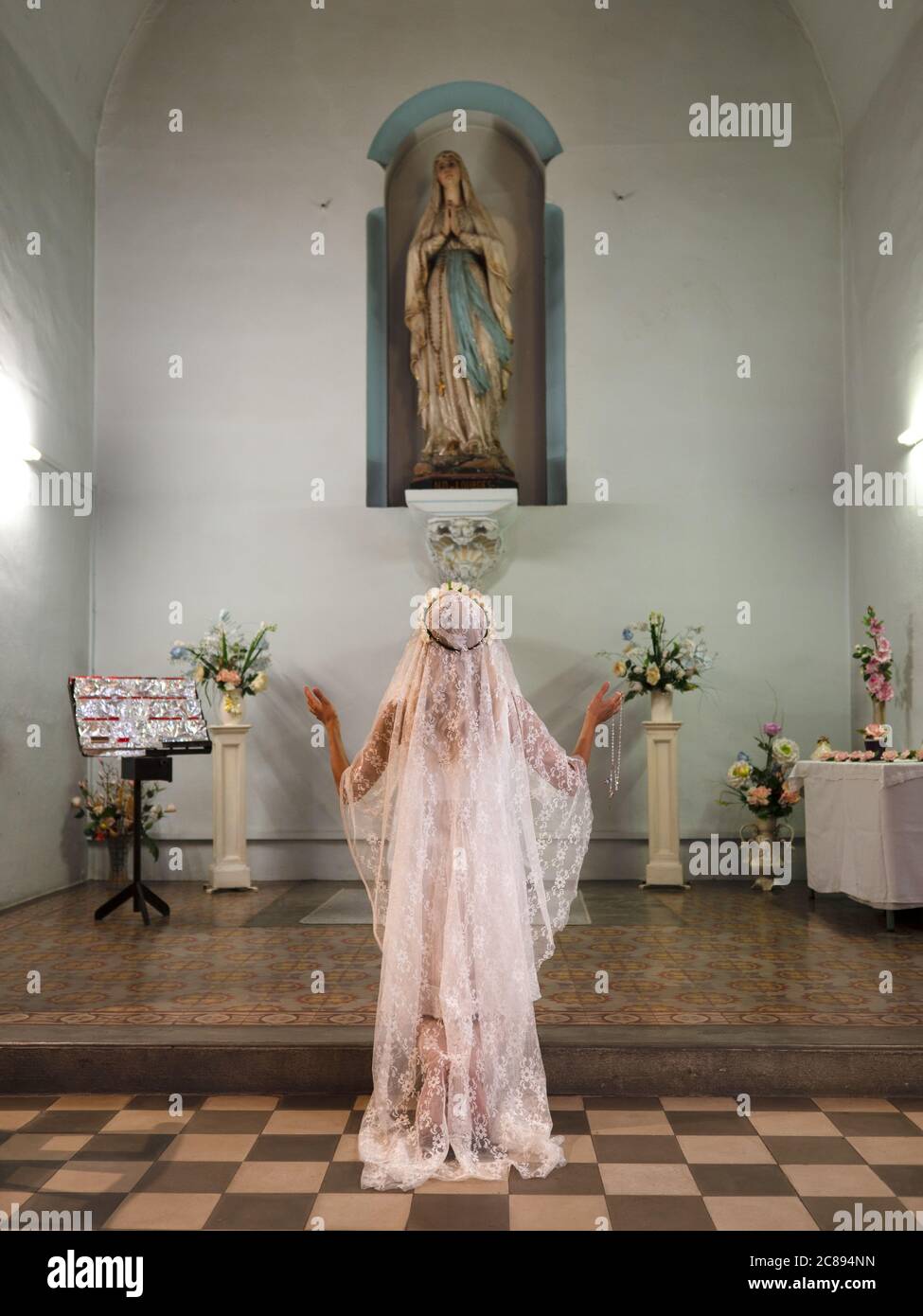 Portrait vertical d'une femme debout et priant dans une église Banque D'Images