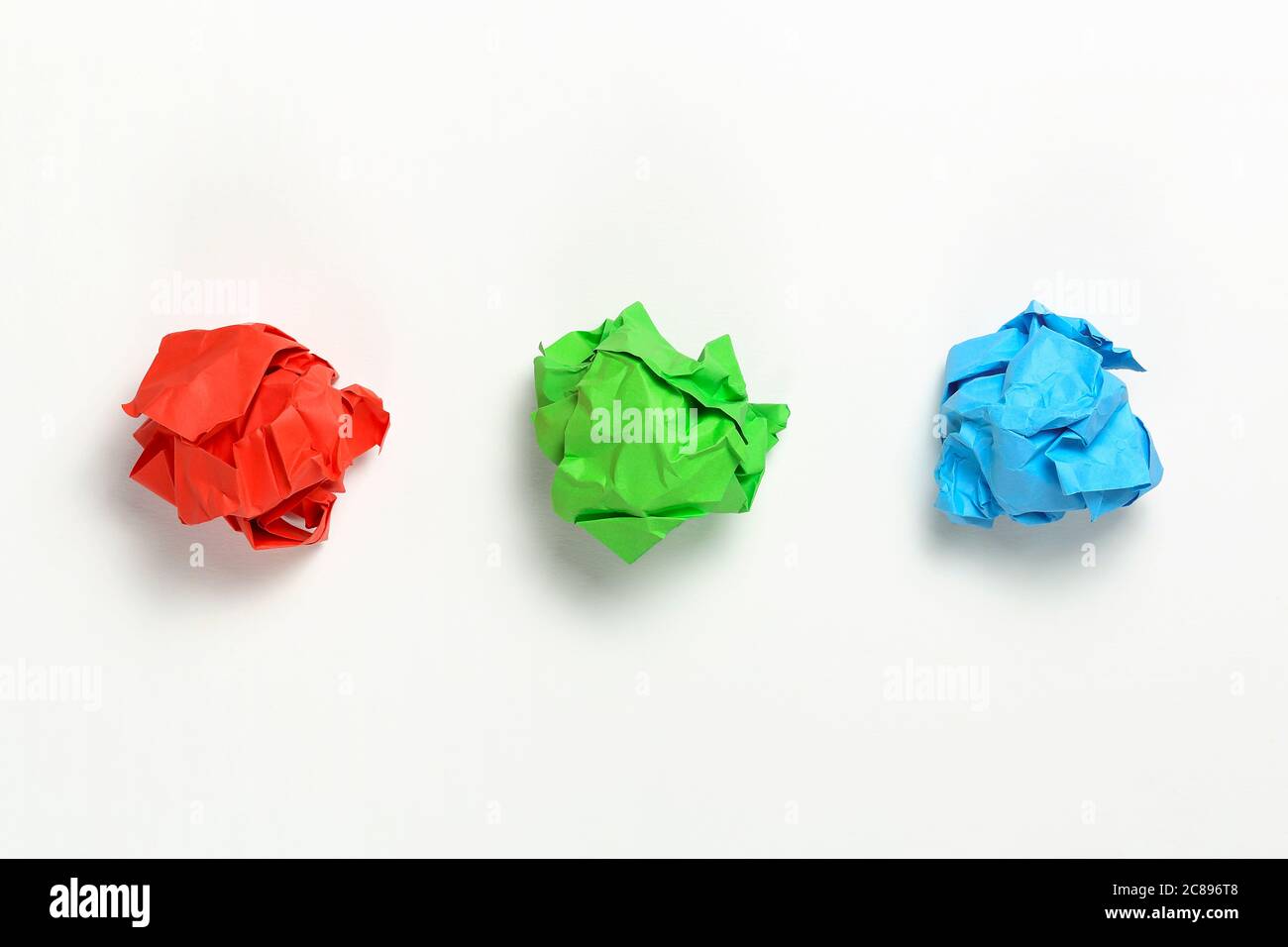 boules de papier rouge, vert et bleu froissés sur une surface blanche Banque D'Images