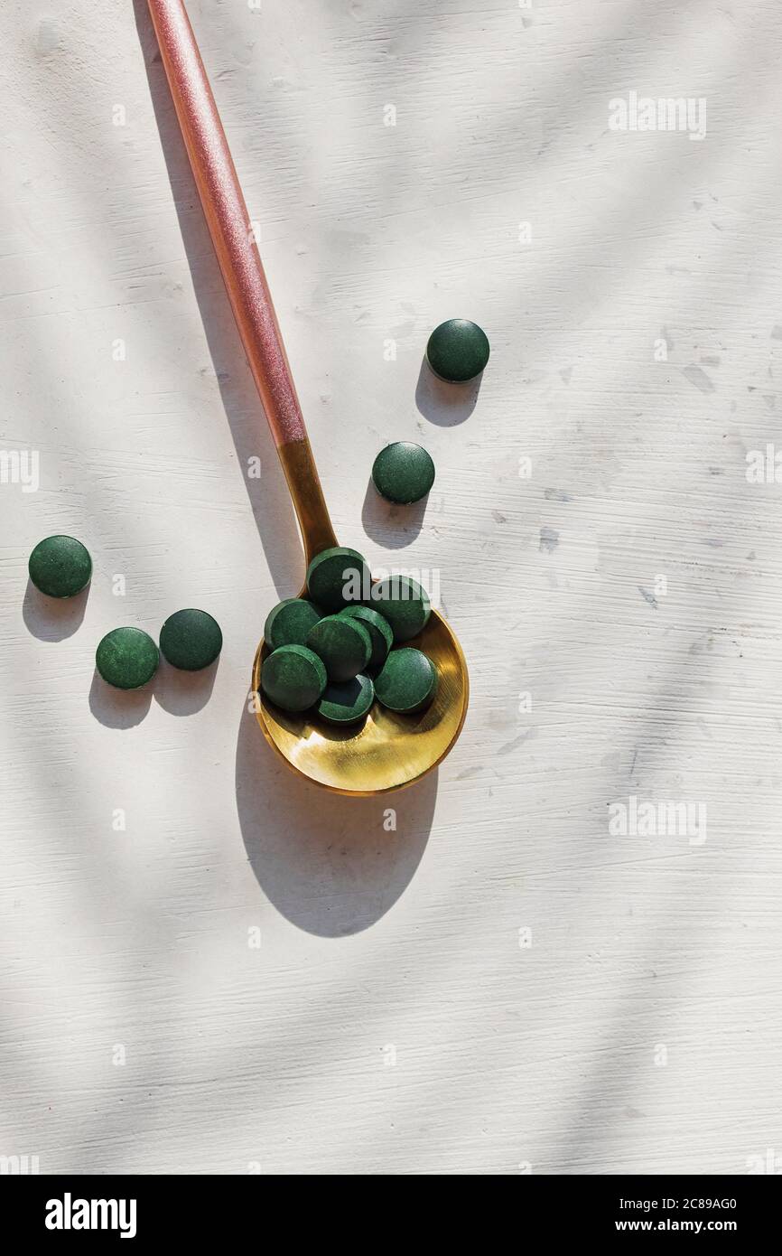 Comprimés de spiruline ou de chlorella dans une cuillère sur une table blanche Banque D'Images
