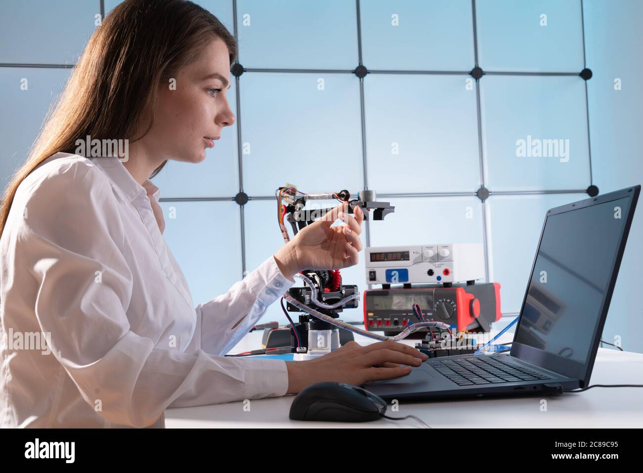 Une jeune femme écrit un algorithme pour le bras du robot. Laboratoire de recherche Sciences du bras robotique modèle. Laboratoire informatique Banque D'Images