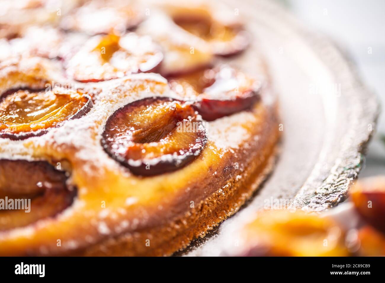 Gâteau aux prunes maison dans une assiette vintage sur une table en bois. Tarte aux prunes avec sucre en poudre Banque D'Images