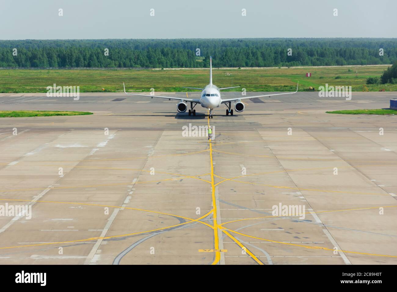 Équipe au sol dans la veste de signalisation. Le superviseur rencontre un avion passager à l'aéroport. L'avion roule sur la place de stationnement Banque D'Images