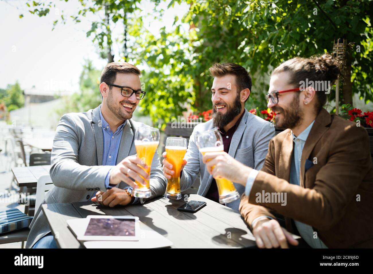 Les jeunes hommes d'affaires boivent de la bière, parlent et sourient tout en se reposant au pub Banque D'Images