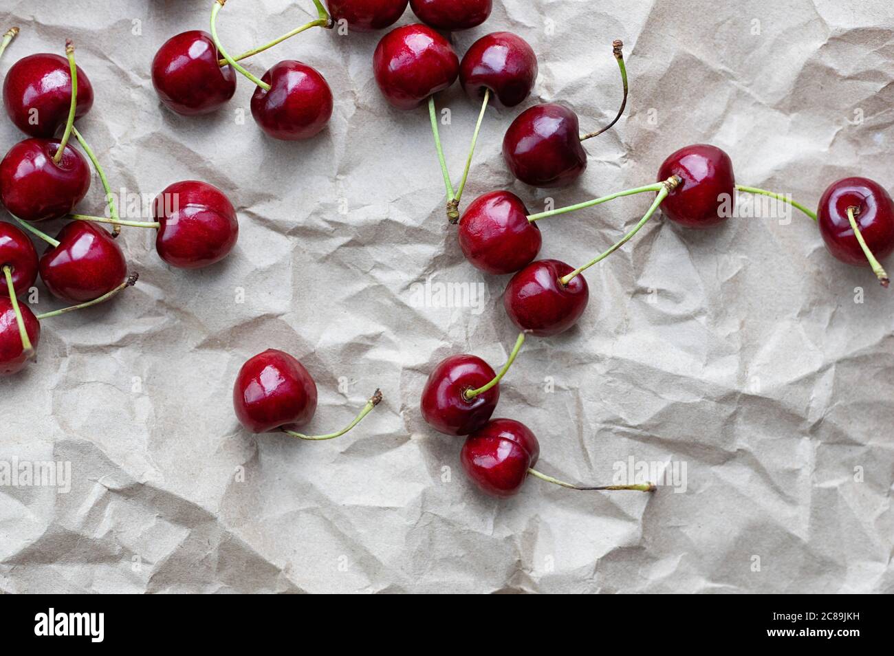 Baies de cerises mûres sur fond de papier artisanal. Mise au point sélective. Gros plan. Copier l'espace. Banque D'Images