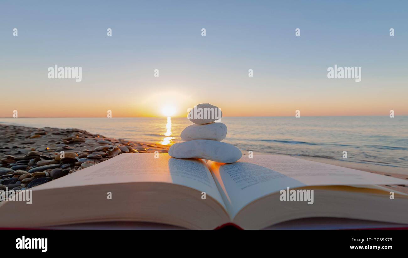 Sérénité sur la plage. Réservez sur la plage avec des galets blancs au lever du soleil. Banque D'Images