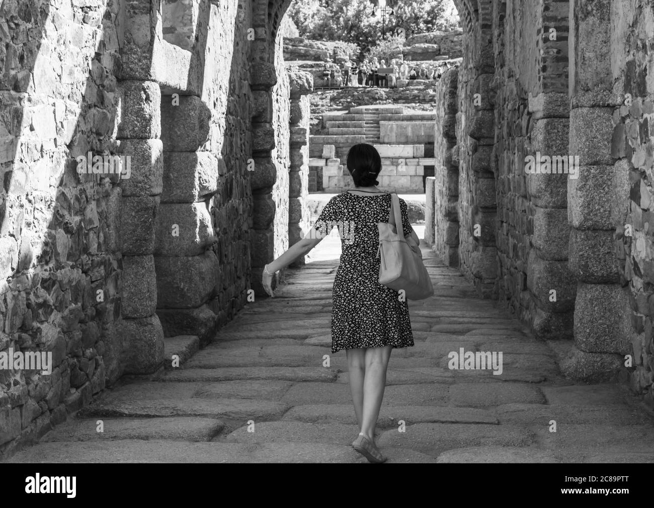 Femme avec son dos avançant dans un couloir de pierre vers l'amphithéâtre romain de Mérida, comme si elle était une actrice ou danseuse qui va sur scène Banque D'Images