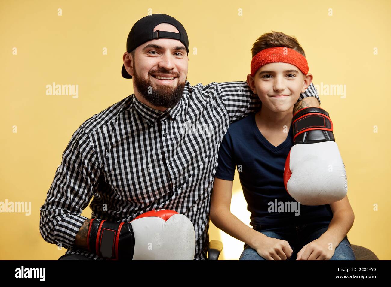 Père et fils s'amusant et se portant avec des gants de boxe isolés sur fond jaune Banque D'Images