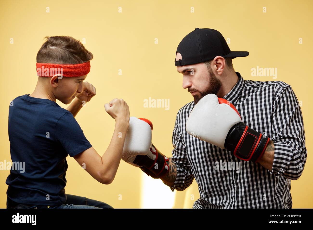 Père et fils pendant l'entraînement de boxe, sur fond jaune Banque D'Images