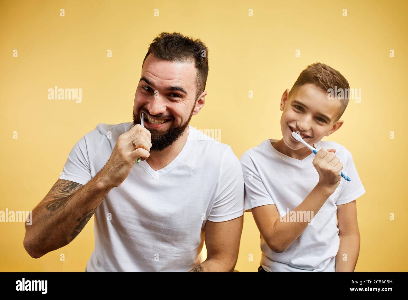 garçon et son père se brossant les dents isolées sur fond jaune Banque D'Images