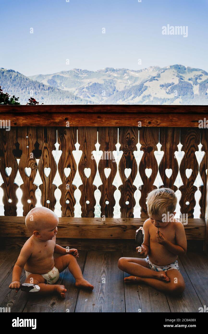 Les enfants mangent de la crème glacée sur un balcon avec des montagnes derrière en été Banque D'Images