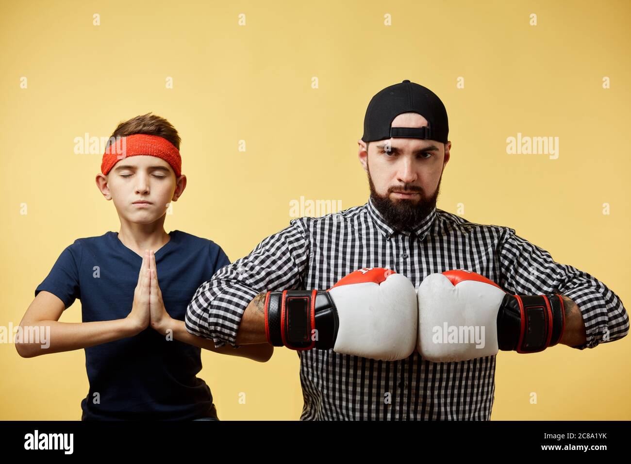 Père et fils avec des gants de boxe faisant un geste namaste sur fond jaune Banque D'Images