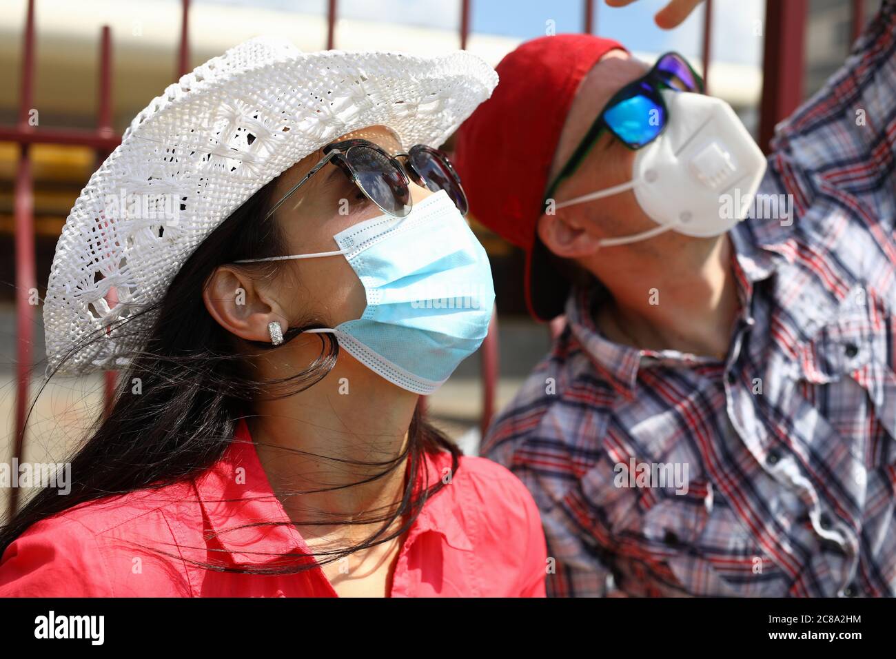 Homme et femme avec masque de protection faciale regarder vers le haut sur le ciel Banque D'Images