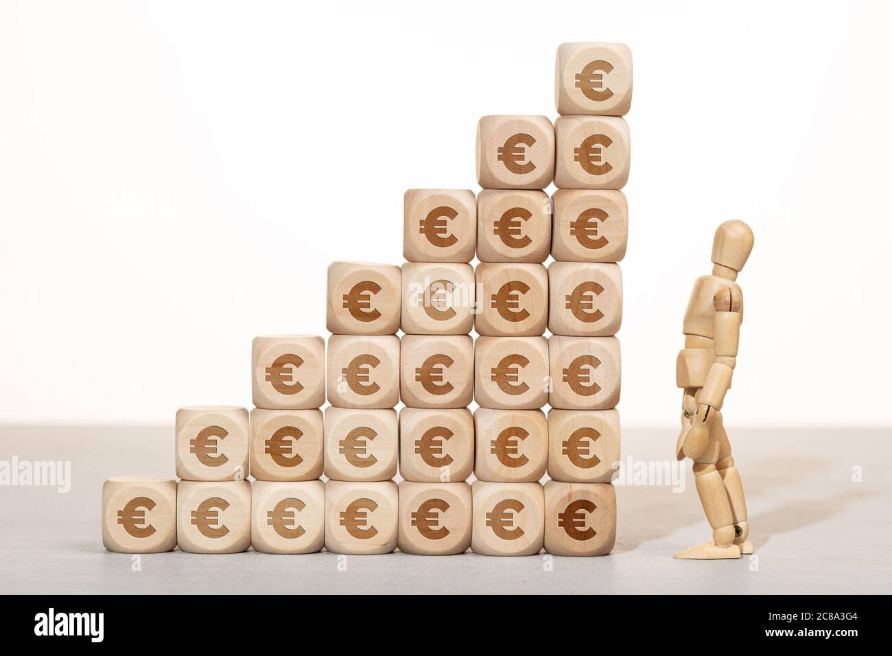 Concept de croissance, de richesse ou de richesse. mannequin en bois regardant un groupe de blocs de bois empilés avec le symbole de l'euro Banque D'Images