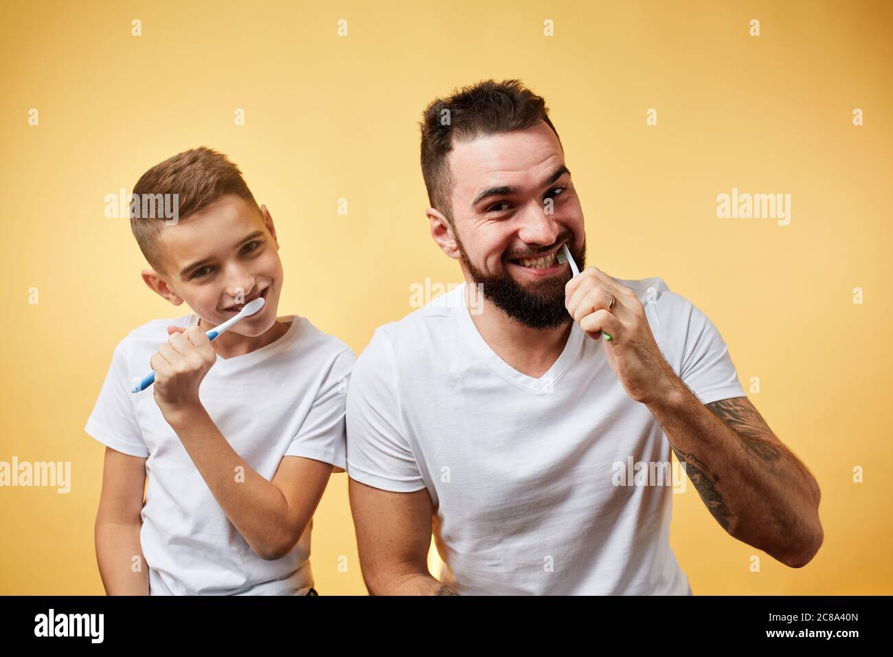 garçon et son père se brossant les dents isolées sur fond jaune Banque D'Images