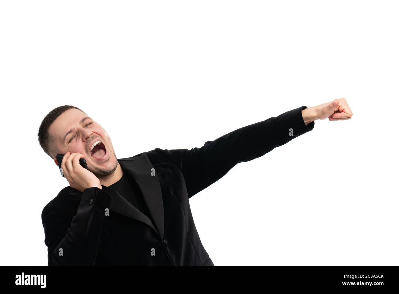 Positif confiant, joyeux jeune homme Manager en costume bleu foncé debout contre un arrière-plan isolé et gestante main tout en communiquant sur mobile Banque D'Images