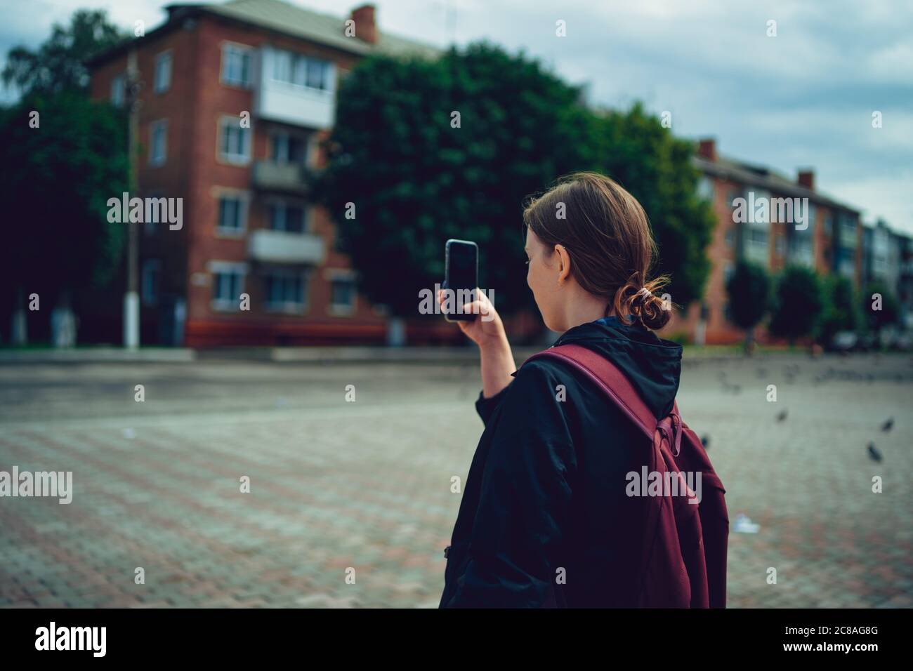 Portrait d'une jeune femme photographiant un paysage urbain avec son smartphone. Une touriste adulte prend des photos sur son téléphone portable. Banque D'Images