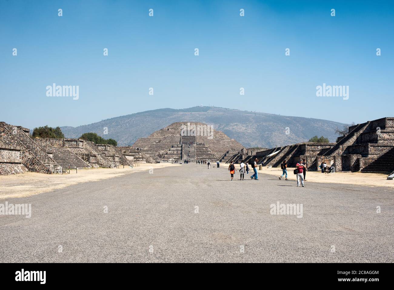 Teotihuacan Avenue Of The Dead Pyramid Of The Moon Mexico | TEOTIHUACAN, Mexique — Les visiteurs traversent l'Avenue of the Dead en direction de la Pyramide de la Lune, le monument en gradins fermant l'extrémité nord de cette avenue cérémonielle. L'avenue s'étend sur environ 1,5 mile (2,4 km) à travers le cœur de la ville antique, et sa grille est inclinée d'environ 15,5 degrés à l'est du vrai nord, un alignement que les chercheurs associent à l'observation solaire et calendaire. Teotihuacan a atteint son apogée entre environ 200 et 550 après J.-C. Banque D'Images