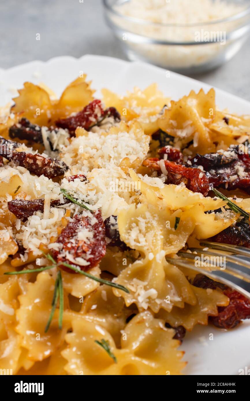 Pâtes avec tomates séchées et parmesan dans une assiette blanche sur la table. Plat alimentaire italien, image verticale Banque D'Images