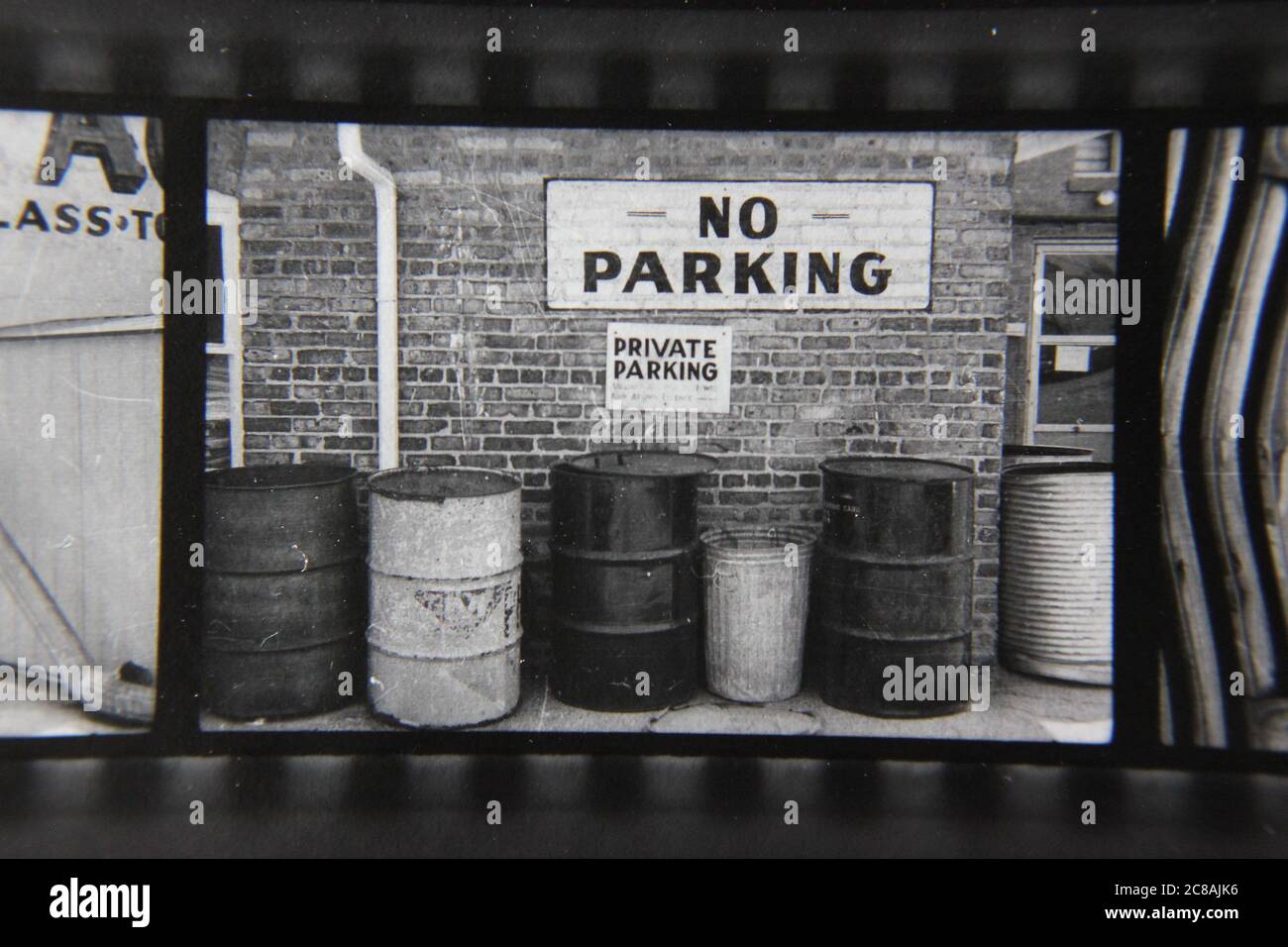 Fin 70s vintage contact imprimé noir et blanc photographie d'un tas de poubelles devant un panneau no parking. Banque D'Images