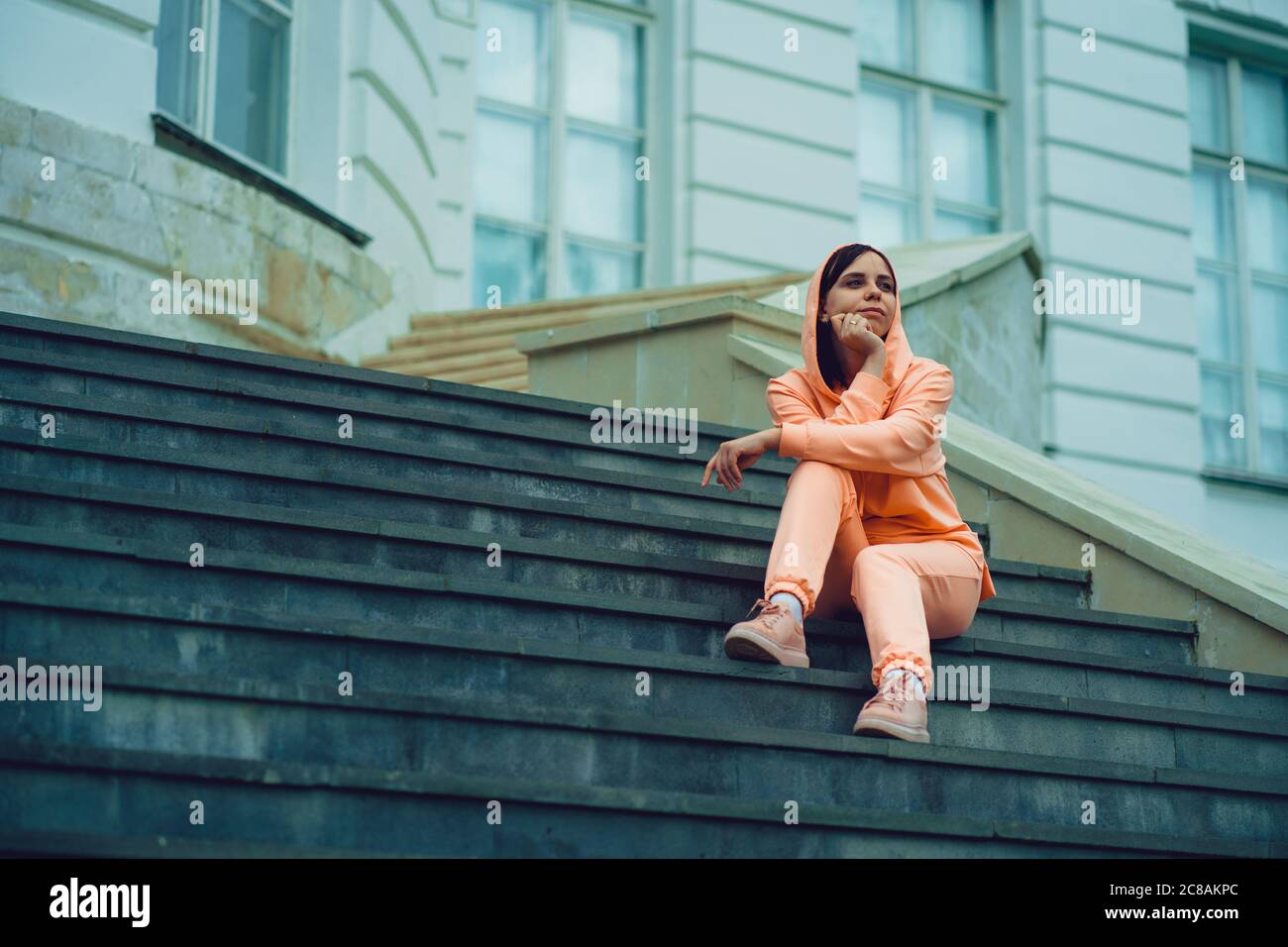 La jeune femme pose sur les escaliers du manoir. Femme adulte assise sur les marches du palais. Banque D'Images