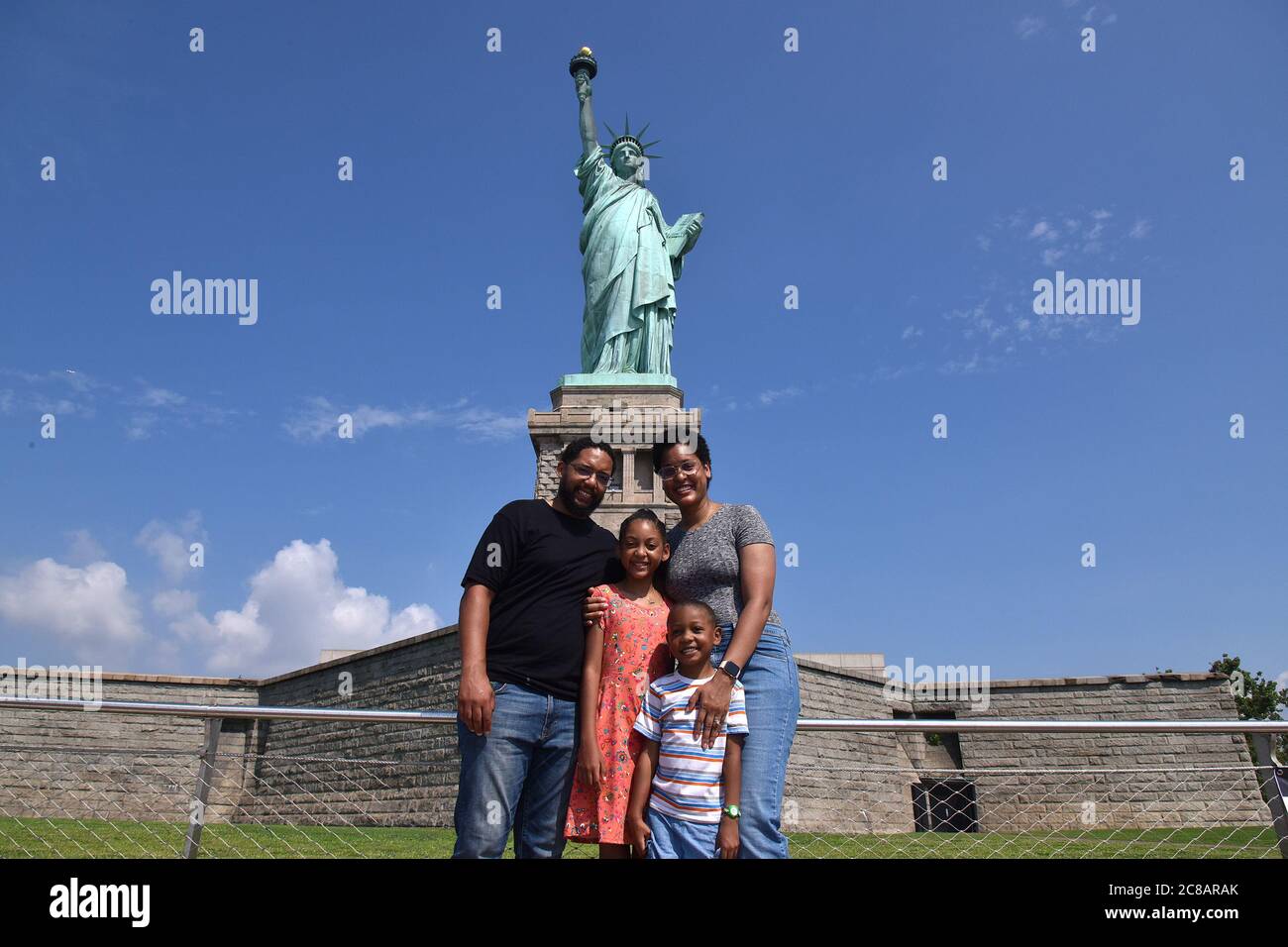 New York, États-Unis. 22 juillet 2020. La famille Fleming se rend en visite devant la Statue de la liberté maintenant que Liberty Park est ouvert aux visiteurs dans le cadre de la réouverture de la phase 4 de New York, Mais l'accès à la Statue de la liberté, y compris la couronne et le piédestal, reste fermé en raison des restrictions de la COVID-19, New York, NY, 22 juillet 2020. Depuis son ouverture lundi, les foules habituelles de dizaines de milliers de personnes ont été absentes, au lieu de cela, un flux lent de quelques centaines de touristes seulement ont été comptés visitant la « Dame liberté ». (Anthony Behar/Sipa USA) crédit: SIPA USA/Alay Live News Banque D'Images