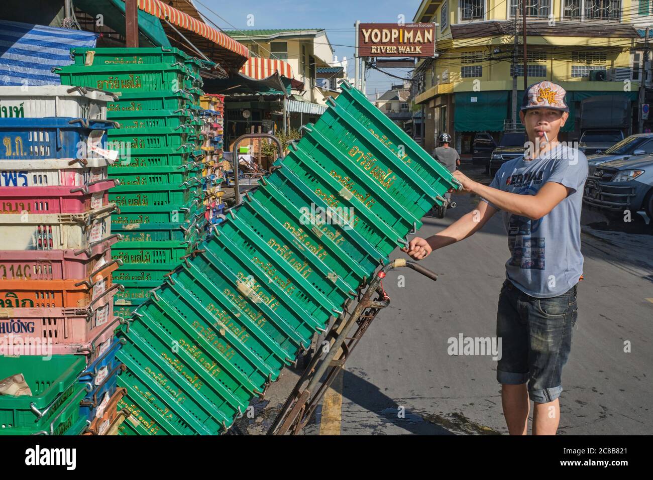 Un portier de Myanmarese (birman) à (marché) Pak Klong Talaat par Yodpiman River Walk, Bangkok, Thaïlande, sur le point de faire le chariot d'une pile de caisses en plastique. Banque D'Images