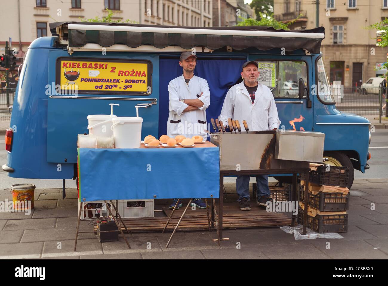 Cracovie / Pologne - 10 juin 2019: Deux hommes en manteaux blancs vendent des hot dogs sur la rue stalle avec une fourgonnette de voyage vintage Banque D'Images