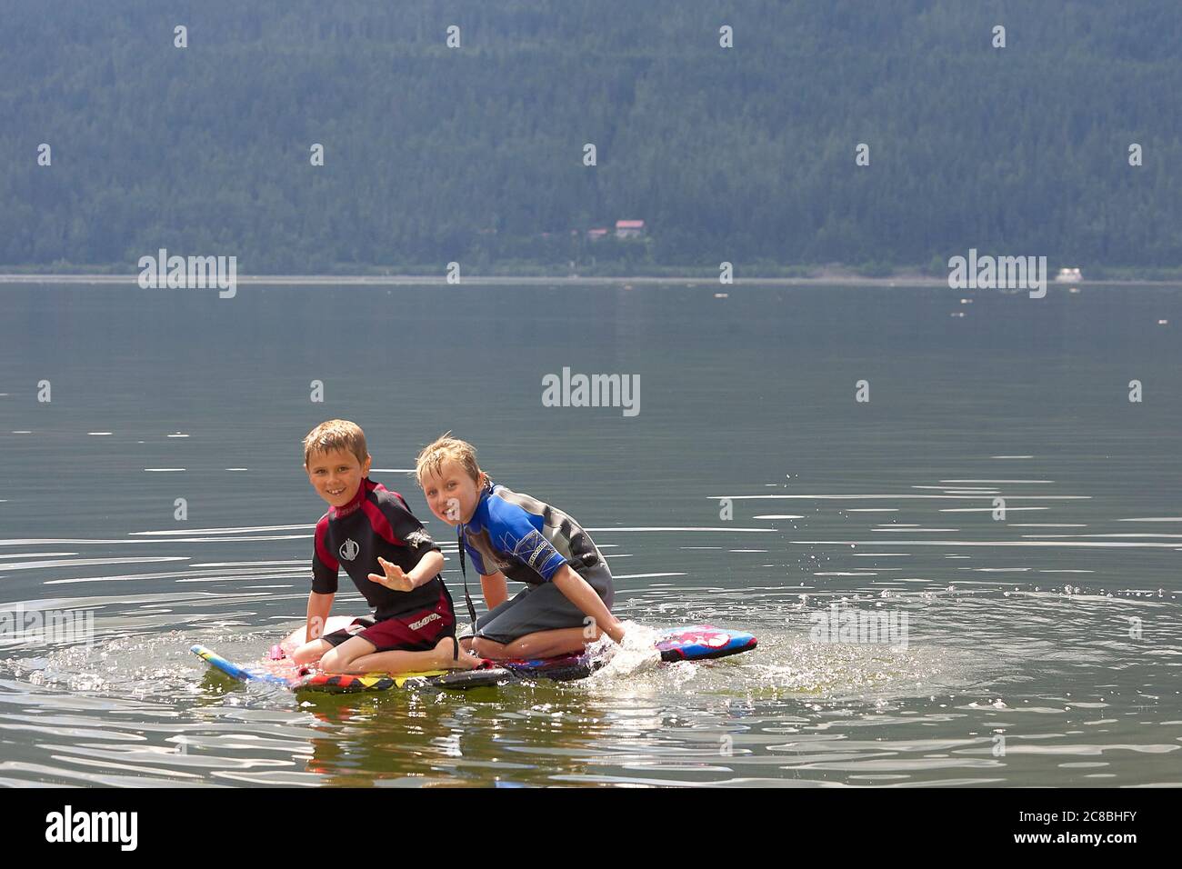 Garçons jouant sur le wakeboard dans le lac. Banque D'Images