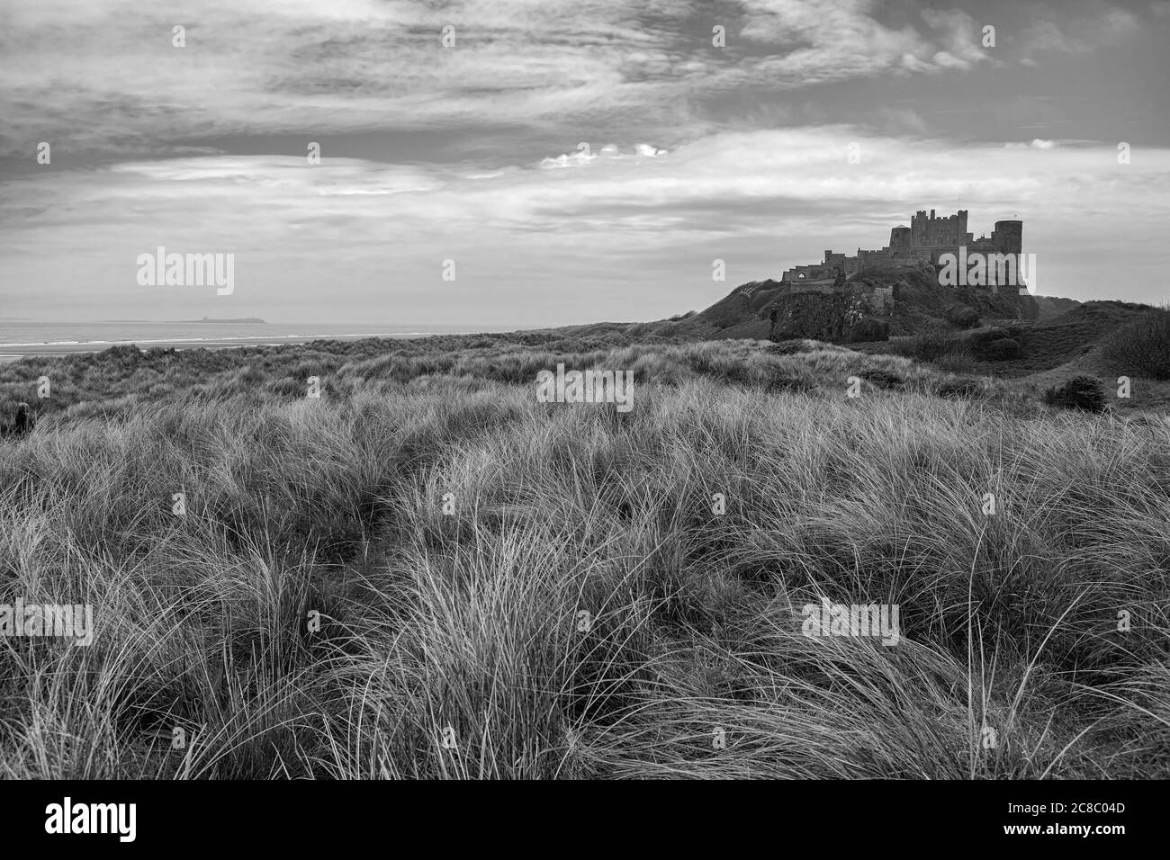 Château de Bamburgh, Northumberland, Angleterre, Royaume-Uni, de l'autre côté des dunes. Version noir et blanc Banque D'Images