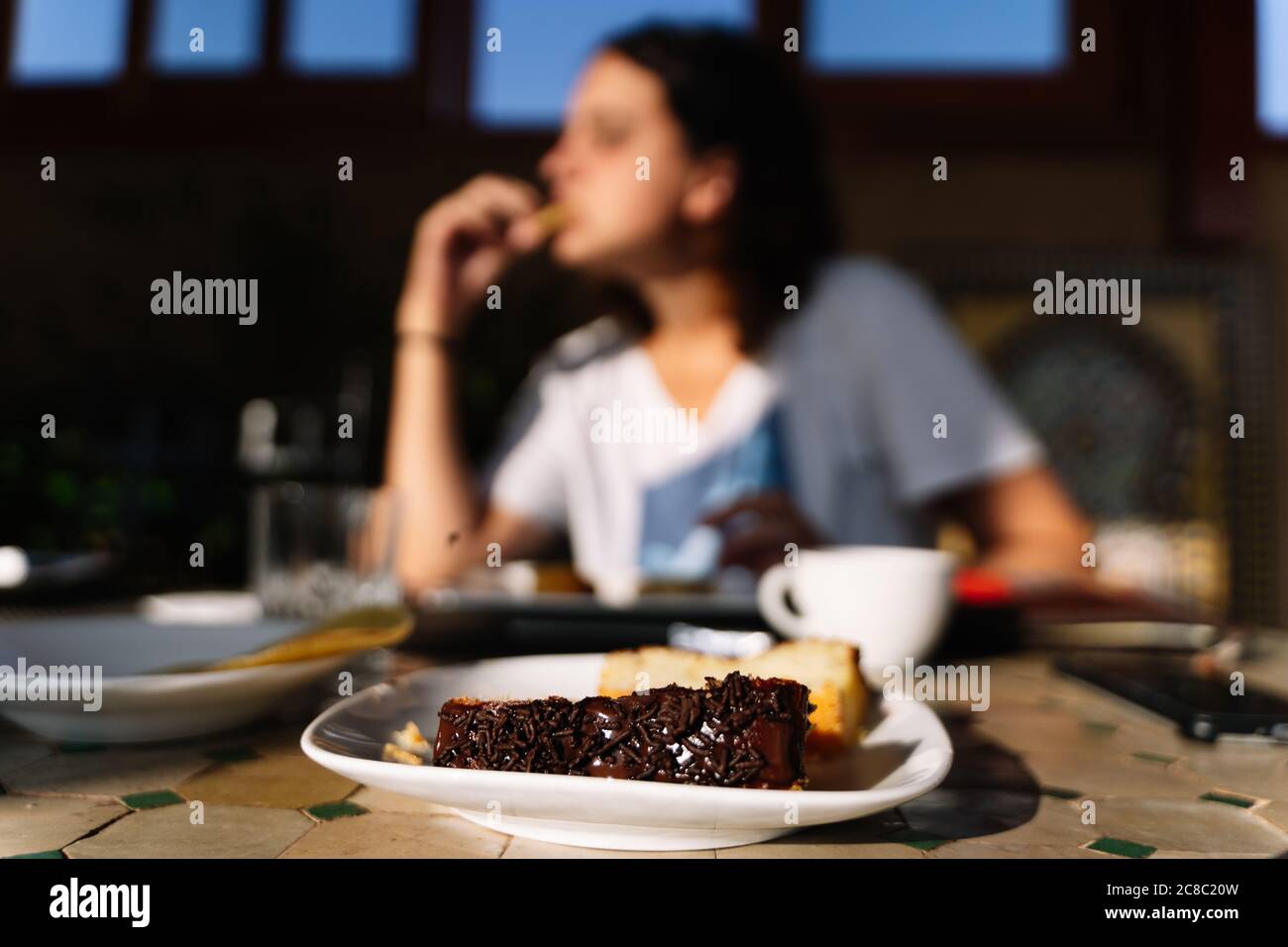 Sélection d'un plat avec un gâteau au chocolat avec une femme mangeant hors de focus dans un restaurant en bois au Maroc Banque D'Images