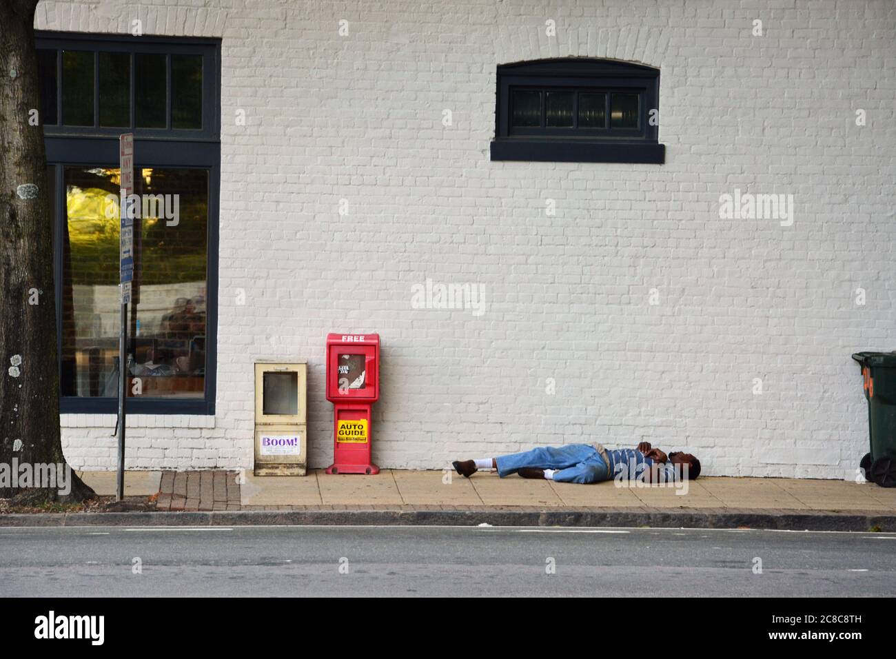 Pendant un après-midi d'été chaud, un homme dort sur le trottoir du centre-ville de Raleigh, en Caroline du Nord. Banque D'Images