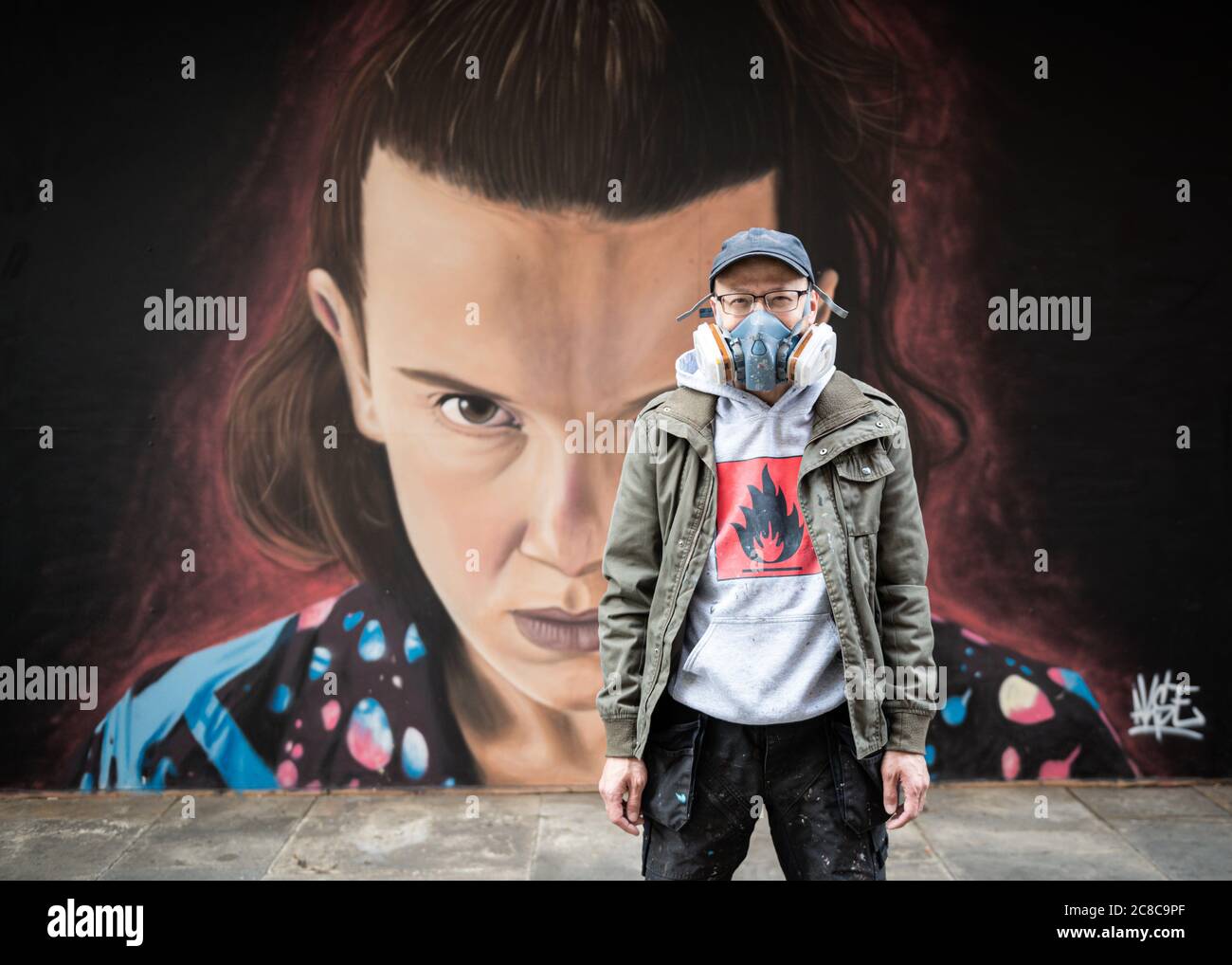 Portrait de l'artiste de rue Akse_P19, debout devant ses peintures murales Banque D'Images