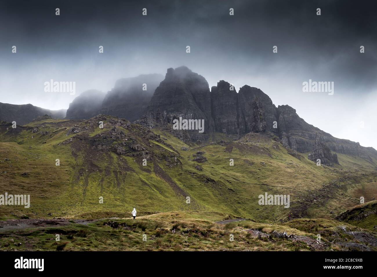 Einsamer Wanderer vor einer schroffen, grünen Berglandschaft in Schottland am Old Man of Storr auf der Isle of Skye Banque D'Images