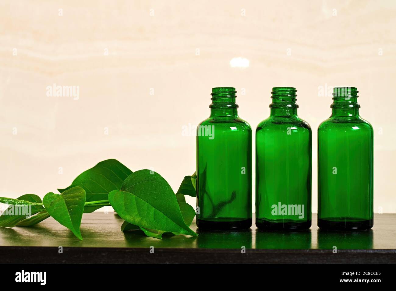 Bouteilles en verre vert avec spray de soin du corps dans la salle de bains sur la table en bois. Produits cosmétiques traditionnels. Espace de copie pour le texte de publicité Banque D'Images