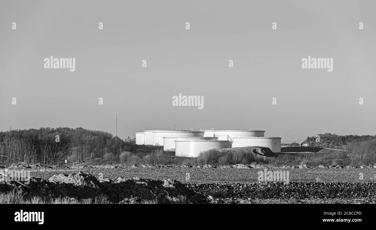 Grands réservoirs d'huile blancs entre quelques petites collines à l'horizon. Banque D'Images