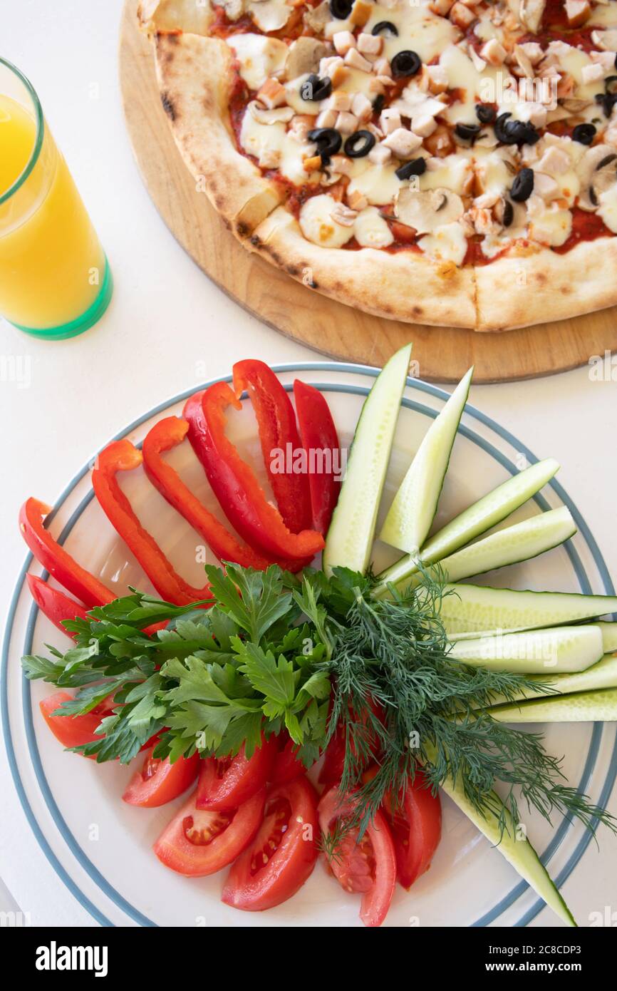 Pizza aux olives et aux champignons et une assiette de frais légumes Banque D'Images